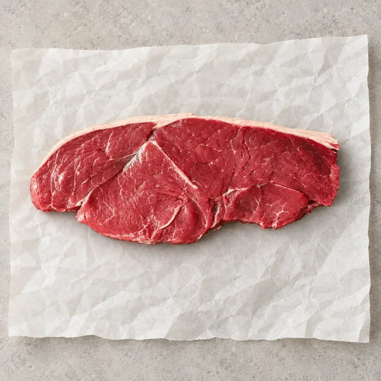 Raw 30oz Caveman Rump Steak by Bromfields Steaks on white parchment paper