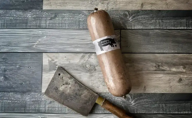 Fruit Pig Brunch Slice sausage with a butcher's cleaver on wooden background. Perfect for a hearty breakfast.