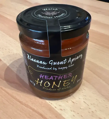 Local Heather Honey 227g jar from Blaenau Gwent Apiary showcasing rich amber color and natural packaging.