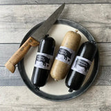 Black pudding and white pudding on a plate with a knife, showcasing artisan quality and freshness.