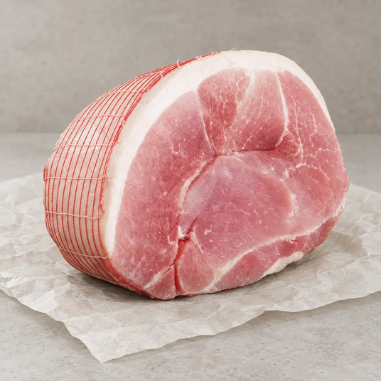 A raw Bromfields Gammon horseshoe joint tied with red netting on white parchment paper.