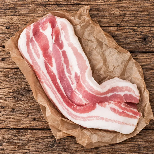 Fresh Bromfields Bacon streaky pork belly on brown parchment paper over a rustic wooden surface