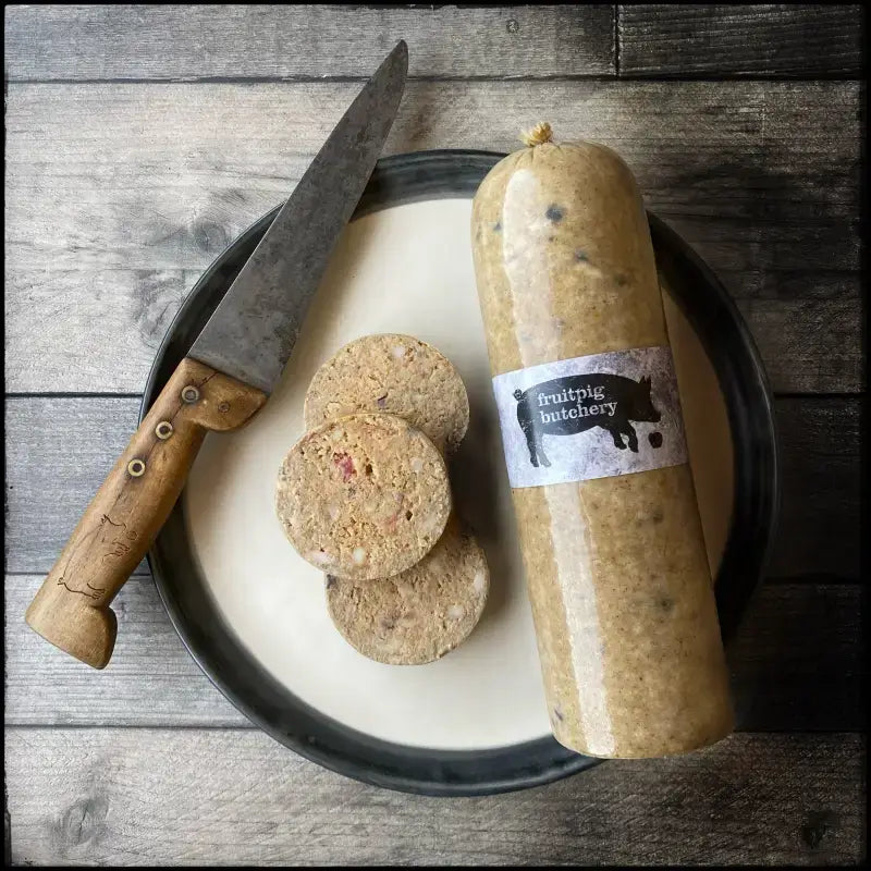 Slices of Fruit Pig White Pudding on a plate with a knife, showcasing the unique texture and presentation of the product.