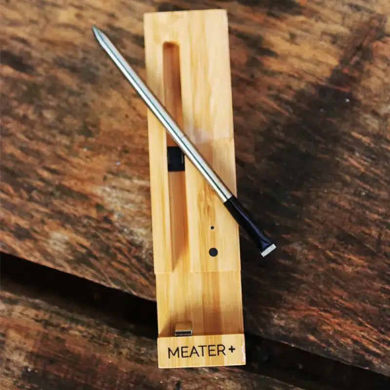 MEATER Plus smart thermometer on a wooden surface, showcasing its sleek design and precision sensor.