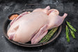 Whole raw Bromfields Game duck on a dark metal tray with rosemary and salt.