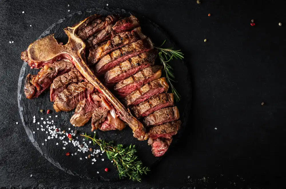 Sliced T-bone steak cooked medium-rare with rosemary and seasonings.