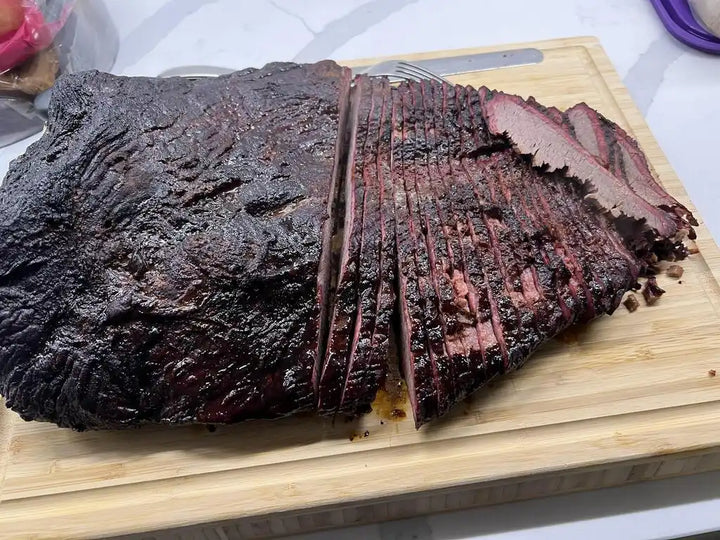 Smoked or grilled beef brisket sliced on a wooden cutting board.